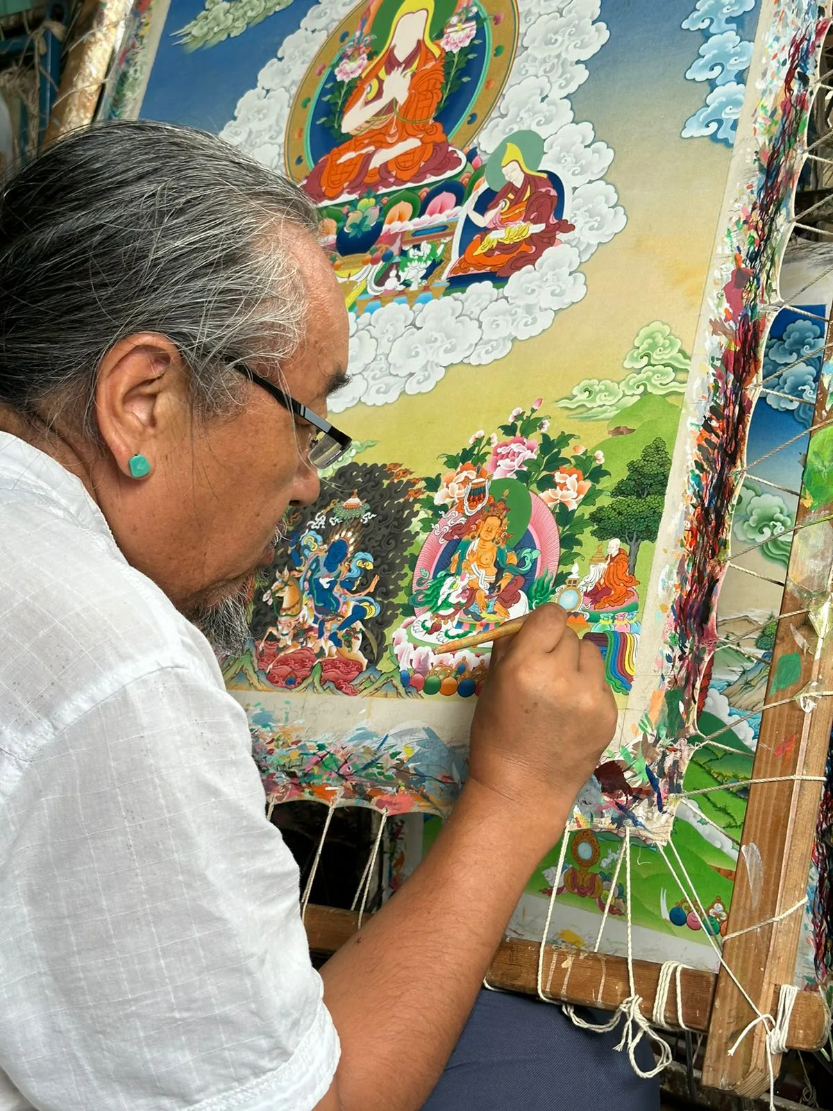 Tibetan thangka artist applying fine detail to a sacred painting