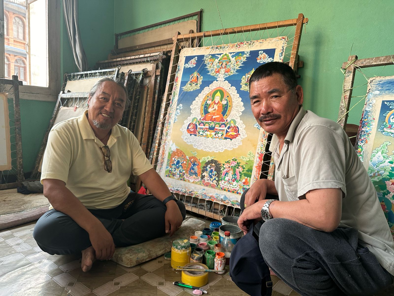 Tenzin Dhargay and Saila Lama seated in the contemporary atelier with thangka paintings