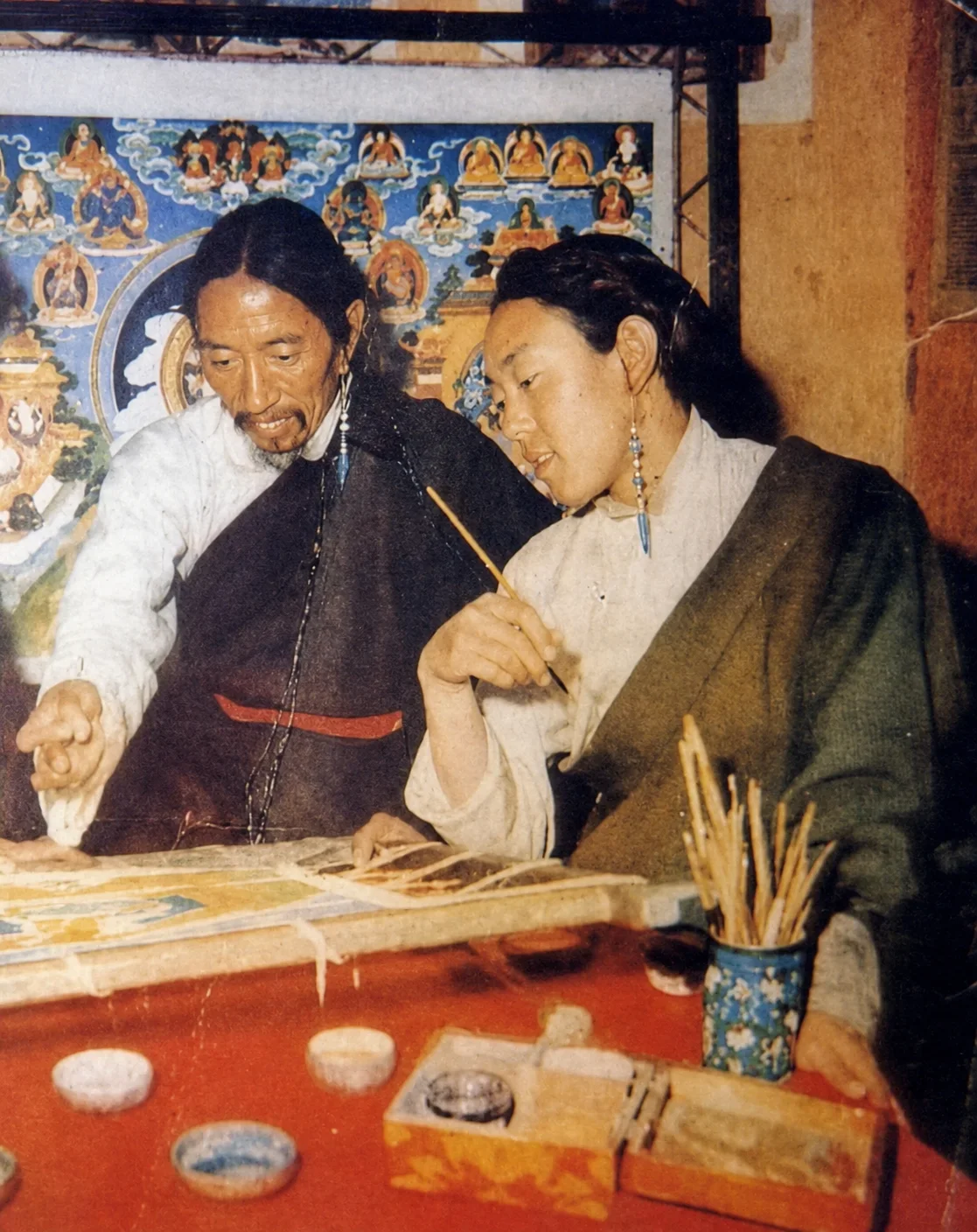Master Sonam Rinchen and Master Rinzin Paljor working together at a thangka painting table