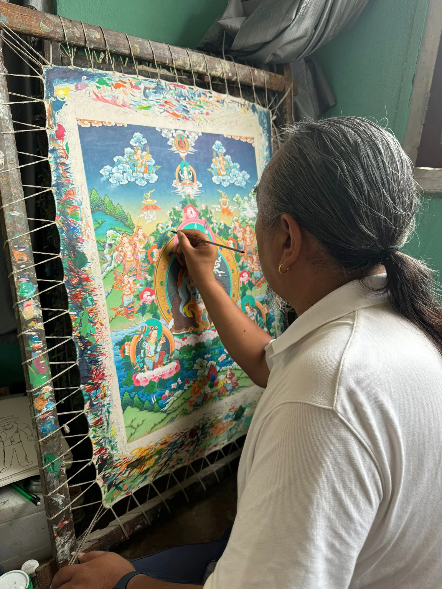 Tibetan thangka artist painting a detailed sacred composition