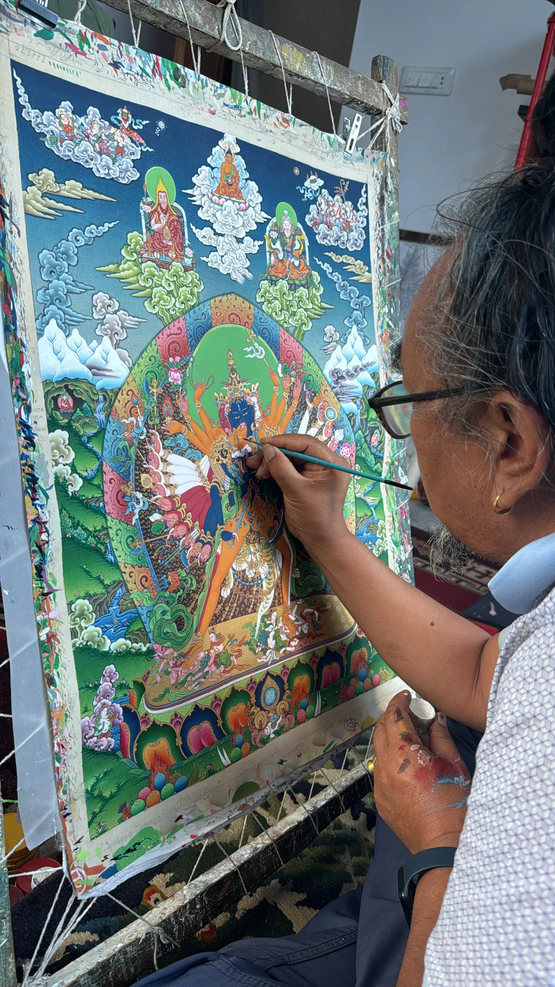 Master Tenzin Dhargay applying fine painted detail to a thangka