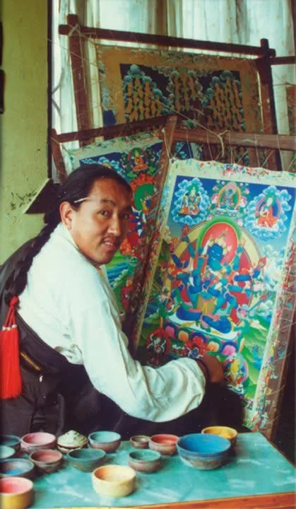 Master Tenzin Dhargay as a younger artist seated at a thangka painting frame