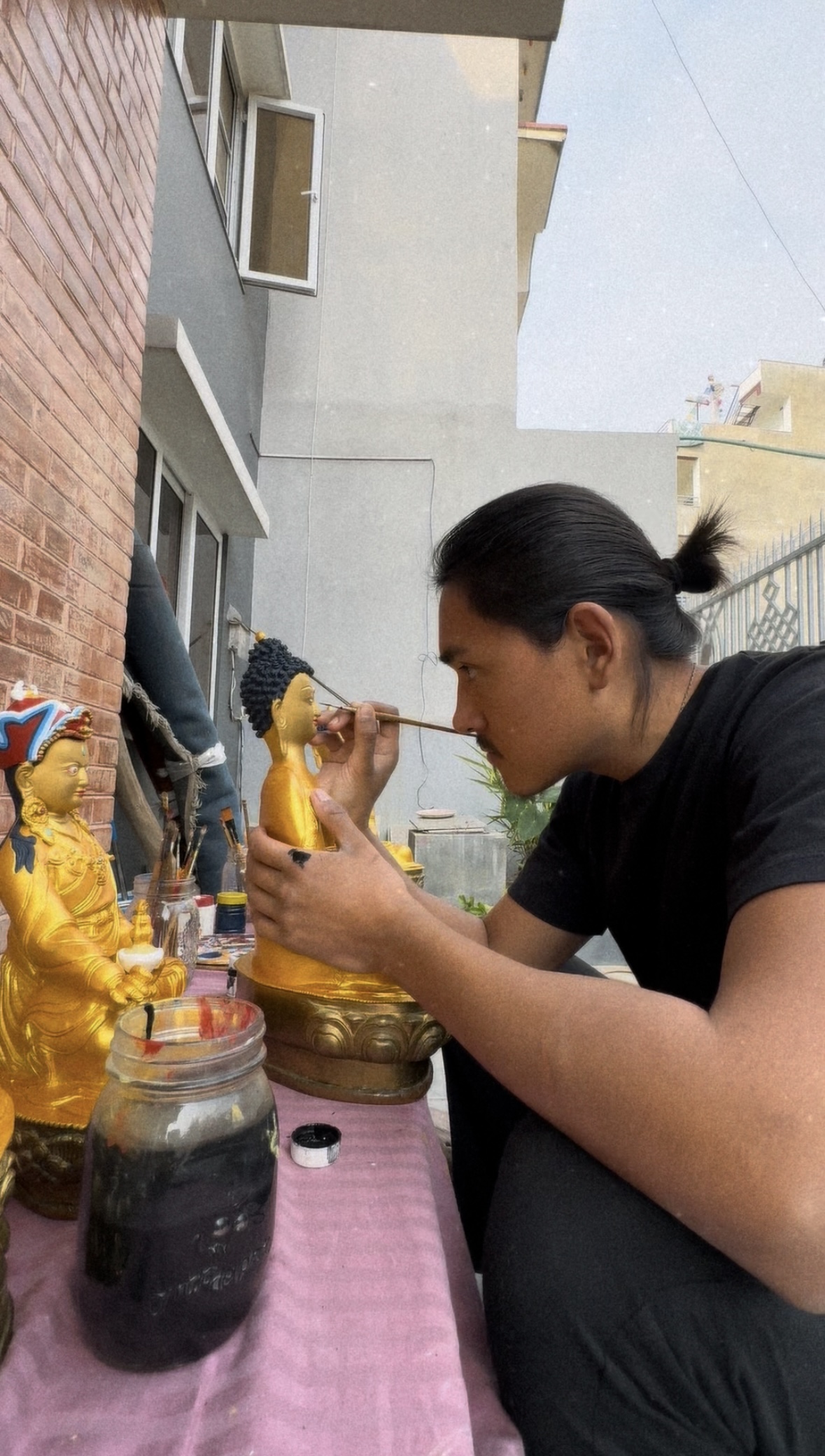 Tenzin Kalden applying gold and painting the eyes of a Buddha statue