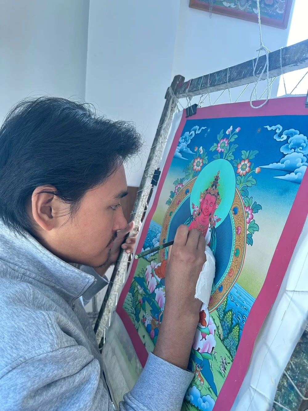 Tenzin Kalden painting fine details on a thangka in the atelier