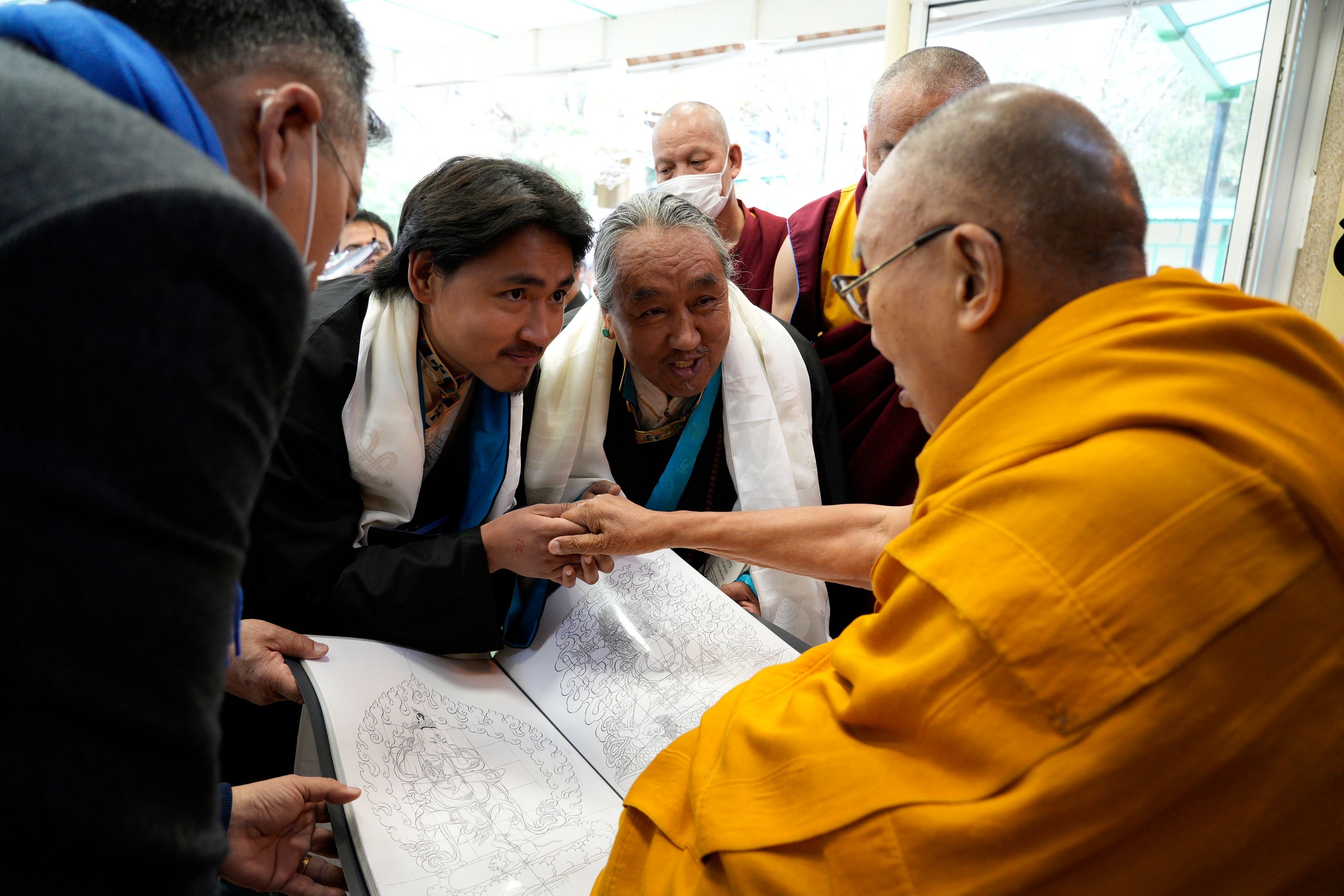 Tenzin Kalden receiving a blessing and presenting thangka drawings as the tenth generation of the lineage